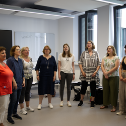 The university choir in a circle in the rehearsal room