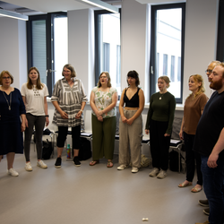 The university choir in a circle in the rehearsal room