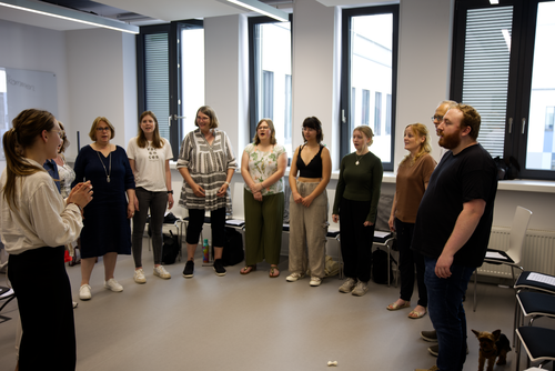 The university choir in a circle in the rehearsal room