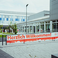 Welcome" banner in front of university building