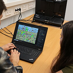 Two people look at an eye-tracking heat map on a laptop, which shows which areas of an image were viewed intensively.