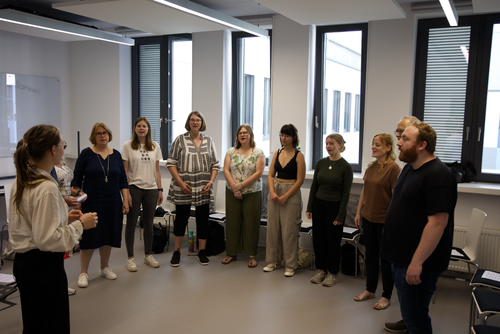 The university choir in a circle in the rehearsal room