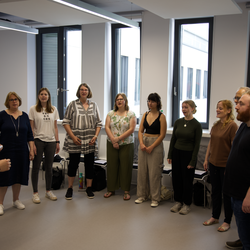 The university choir in a circle in the rehearsal room