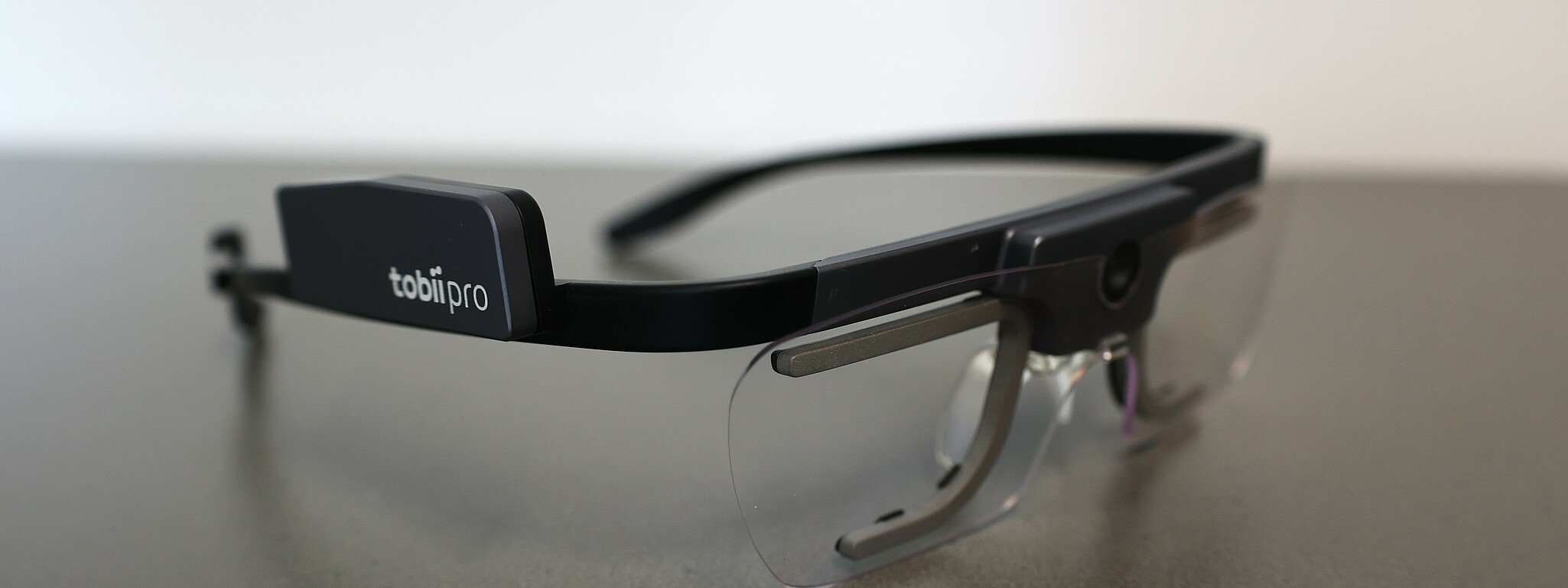 Image of the eye tracking glasses, lying on a surface. The name "tobiipro" can be recognized