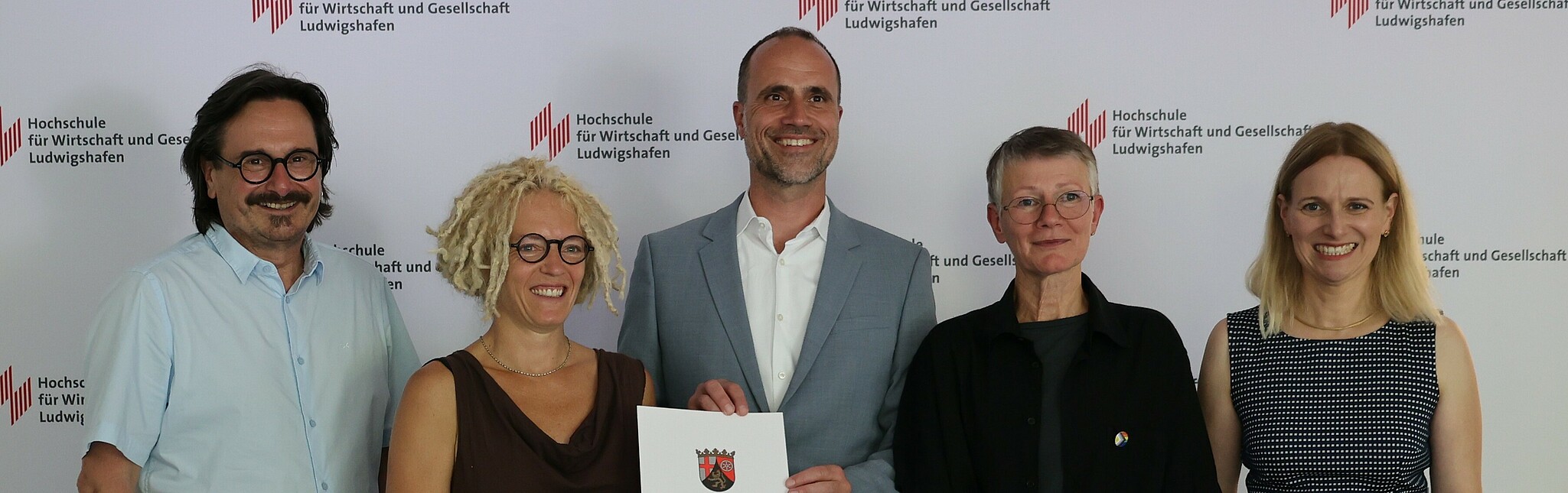 Science Minister Clemens Hoch (center) hands over the funding decision for the "PRO.SOZIAL" project at Ludwigshafen University of Business and Society to the applicants Prof. Dr. Marion Ott (2nd from left) and Prof. Dr. Karen Wagels (2nd from right) in the presence of Dean Prof. Dr. Peter Rahn and Vice President Prof. Dr. Edith Rüger-Muck.